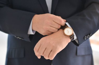 Kol saatlerini düzelt, yakın plan, giyinme, erkek tarzı, şık bir adam. Zarif genç yakışıklı adam. Erkek ceketi, düğmeyi elle kapat. İş biçimi.