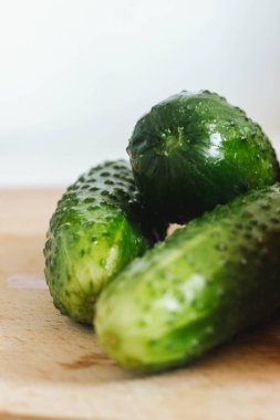Tahta masada beyaz arka planı olan taze salatalıklar.
