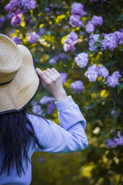 Leylak desenli hasır şapkalı genç kadın.