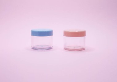 Pembe arka planda iki boş kozmetik kavanozu