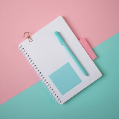 Renkli arkaplanda kalem ve çıkartmaları olan boş not defterinin düz düzeni