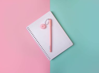 Renkli arka planda pembe kalemli boş not defterinin düz düzeni