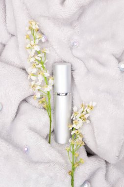 Gri arka planda kiraz çiçekleri olmayan zarif metalik kozmetik şişe.