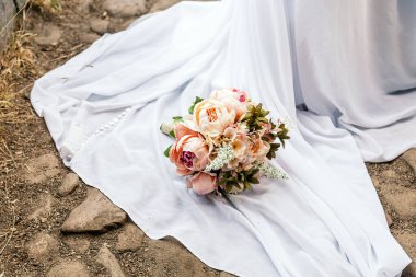 Güzel bir buket düğün şakayığını yakın bir yolda gelinliğin üzerinde