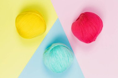 Düz nane yeşili, mercan pembesi ve koyu sarı pamuk topları geometrik pastel arka planda.