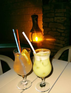 İki kokteyl pina colada ve bardakta aperol spreyi akşam lambanın arka planında.           