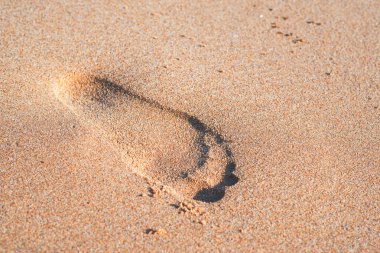 Gün batımında kumdaki ayak izleri. Deniz dalgaları ile güzel kumlu tropik plaj