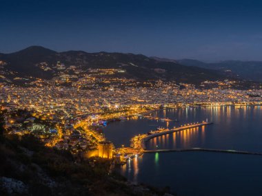 Alanya, Türkiye. Güzel bir panoramik gece manzarası Alanya şehri, Akdeniz, kırmızı kule, Alanya Kalesi 'nin deniz feneri. Tatil kartpostal arkaplanı
