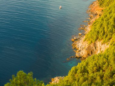 Alanya, Türkiye. Akdeniz 'deki Alanya Kalesi' nden güzel bir manzara, gün batımında kayalıklar ve kayıklar. Tatil kartpostal arkaplanı