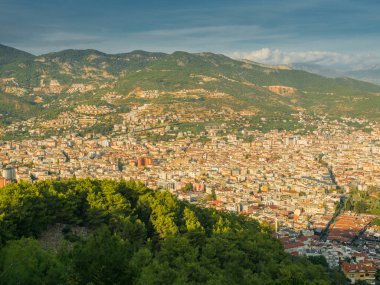 Alanya, Türkiye. Alanya şehrinin Alanya Kalesi 'nden gün batımında dağların arka planında güzel bir manzara. Tatil kartpostal arkaplanı