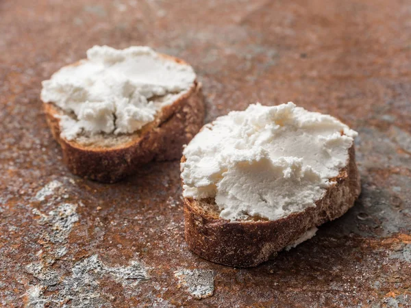 Bruschetta de pan integral con queso crema de cuajada suave blanco sobre un fondo grunge de jengibre. Primer plano — Foto de Stock