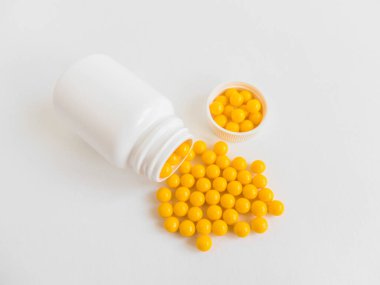 Vitaminler. Antiviral ilaç hapları. Yuvarlak sarı sağlıklı haplar ve beyaz arka planda ilaç şişesi. Asgari konsept