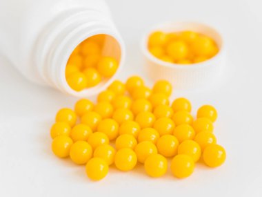Vitaminler. Antiviral ilaç hapları. Yuvarlak sarı sağlıklı haplar ve beyaz arka planda ilaç şişesi. Asgari konsept