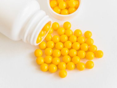 Vitaminler. Antiviral ilaç hapları. Yuvarlak sarı sağlıklı haplar ve beyaz arka planda ilaç şişesi. Asgari konsept