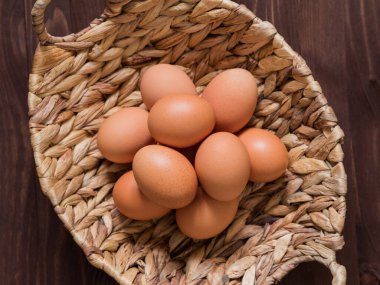 Ahşap bir arka planda hasır sepette turuncu tavuk yumurtası. Paskalya konsepti. Minimalizm. Üst görünüm.