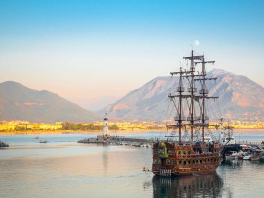 Alanya, Türkiye. Korsan yelkenli eğlence gemisi akşamları bir deniz feneriyle körfezde geziyor. Tatil kartpostal arkaplanı