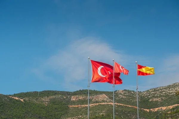 Alanya, Türkiye. Mavi gökyüzü ve dağların arkasında Türkiye 'nin kırmızı bayrakları. Tatil kartpostal arkaplanı