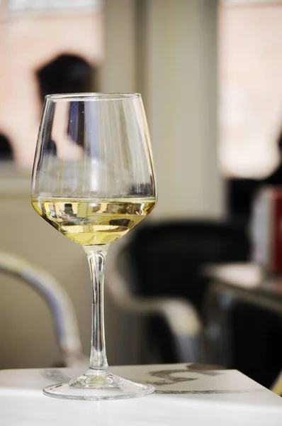 Close-up of a glass of white wine on a bar\'s table outside. Background out of focus