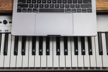 Bir piyanonun siyah beyaz tuşları ve dizüstü bilgisayarın klavyesinin en üst ayrıntıları