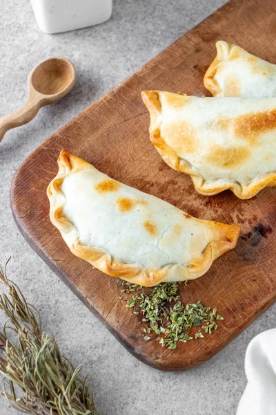 Geleneksel Arjantin sıcak yemekleri et ve soğandan yapılır. Tahta tahtada ve beyaz arka planda empanada adı verilir..