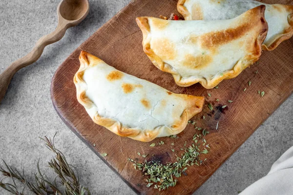 Geleneksel Arjantin sıcak yemekleri et ve soğandan yapılır. Tahta tahtada ve beyaz arka planda empanada adı verilir..