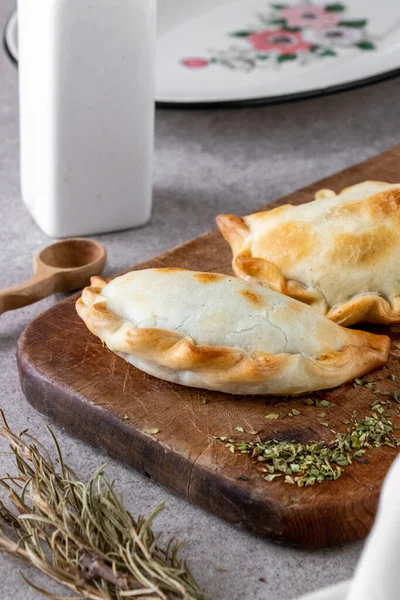Geleneksel Arjantin sıcak yemekleri et ve soğandan yapılır. Tahta tahtada ve beyaz arka planda empanada adı verilir..