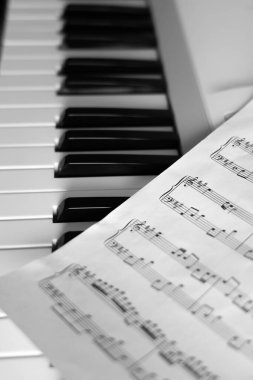 Müzik sayfası piyanonun siyah beyaz tuşlarına uzanır