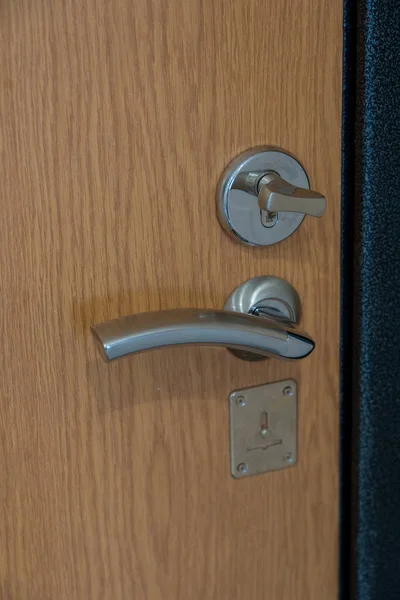 Brown wooden door with metal door handle and metal door lock