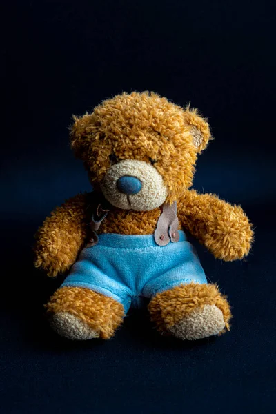 Gelber Brauner Teddybär Blauer Hose Sitzt Auf Dunkelschwarzem Hintergrund — Stockfoto