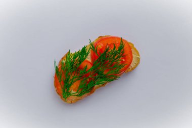 Tereyağlı bir parça ekmek, kırmızı domates dilimleri ve beyaz arka planda izole edilmiş taze yeşil dereotu.