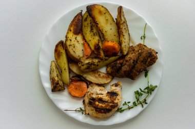 Izgara et dilimleri ve beyaz tabakta kızarmış patatesten oluşan tabağın üstü açık.