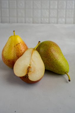 İki tam olgun armut ve bir armut yarısı çimento yüzeyinde, makro manzaralı.