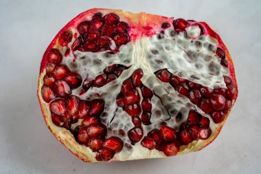 Olgun kırmızı narların yarısı beton yüzeyde yatıyor.