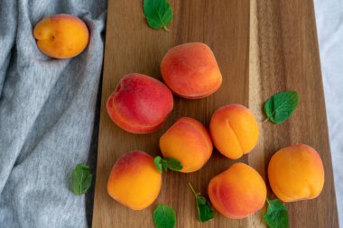 Tahta kesme tahtasının üzerinde duran bir sürü olgun kayısıların üst görüntüsü.