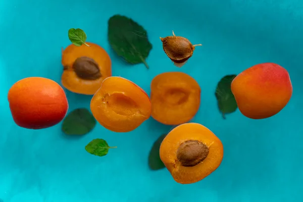 Reife Aprikosenscheiben Und Minzblätter Fliegen Über Die Blaue Oberfläche — Stockfoto