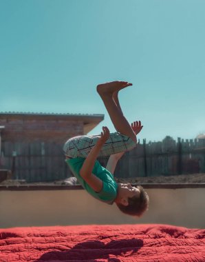 Bir çocuk trambolinde zıplıyor. Şişme yatakta zıplamak.