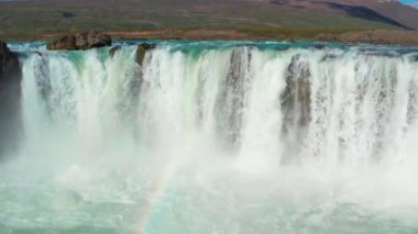 Gökkuşağıyla Godafoss Şelalesi üzerinde uçan bir uçak.
