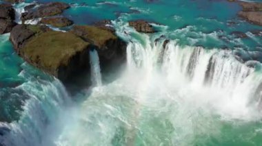 Gökkuşağıyla Godafoss Şelalesi üzerinde uçan bir uçak.