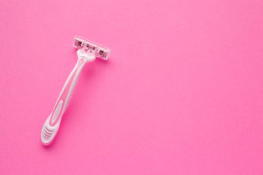 Pembe arka planda pembe plastik tıraş makinesi olan kadın. Mesaj için yer var. Tek kullanımlık kadın traş makinesi..
