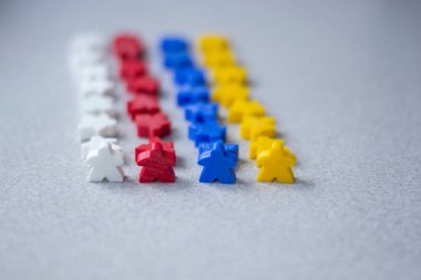 Gri arka planda izole edilmiş renkli takımlar. Küçük insan figürleri. Masa oyunları konsepti. Plastik minyatürler.