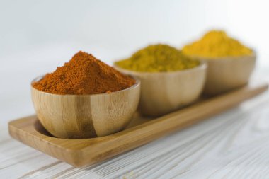 Ahşap kaselerde çeşitli baharatlar var. Paprika, zerdeçal, köri.