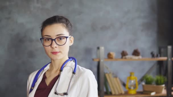Портрет жінки-лікаря зі стетоскопом, дивиться на камеру, посміхається . — стокове відео