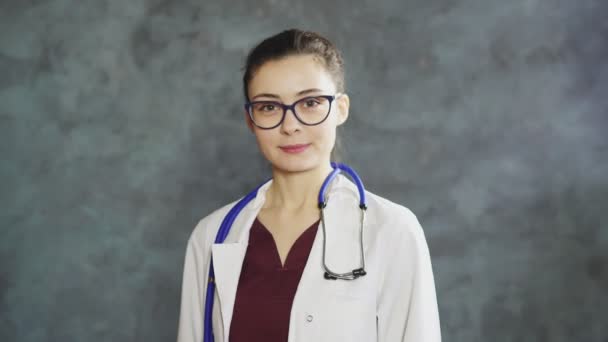 Portrait de heureuse jeune femme médecin avec des lunettes montrant signe correct — Video