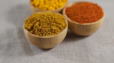 Tahta kaselerde çeşitli baharatlar var. Paprika, zerdeçal, köri. Çevirme videosu.
