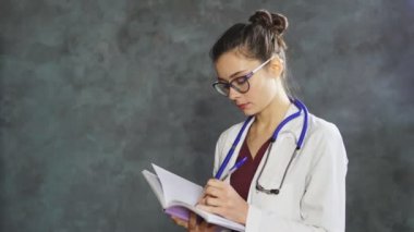 Beyaz üniformalı profesyonel kadın doktor portresi not defterine not alıyor.