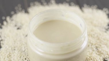 Susam yağı, tahini. Masadaki kavanozdaki beyaz susamlı krema ezmesi. Doğal beslenme ve organik gıda kaşığı.