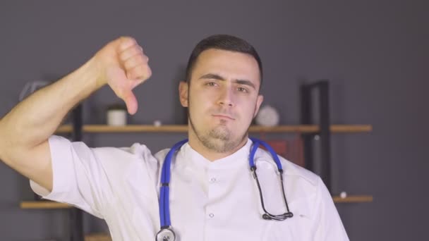 Young man doctor showing thumb down sign with negative expression. No gesture — ストック動画