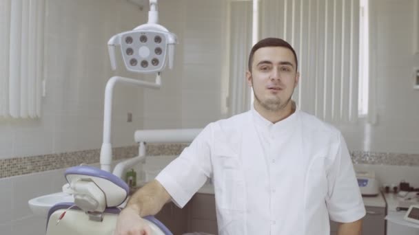 Veselý zubař mluví a dívá se do kamery. Vysvětlete něco na zubní klinice.. — Stock video