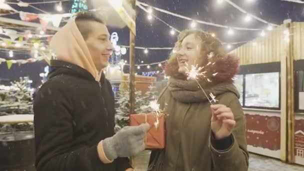 Opgewonden jong stel viert nieuwjaar met bengaalse lichtjes of sterretjes op kermis — Stockvideo
