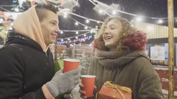 Excited young couple celebrating new year holding gifts and smiling at Christmas fair — Stock Video